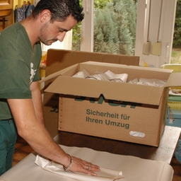 Moving packing services - man wrapping glasses